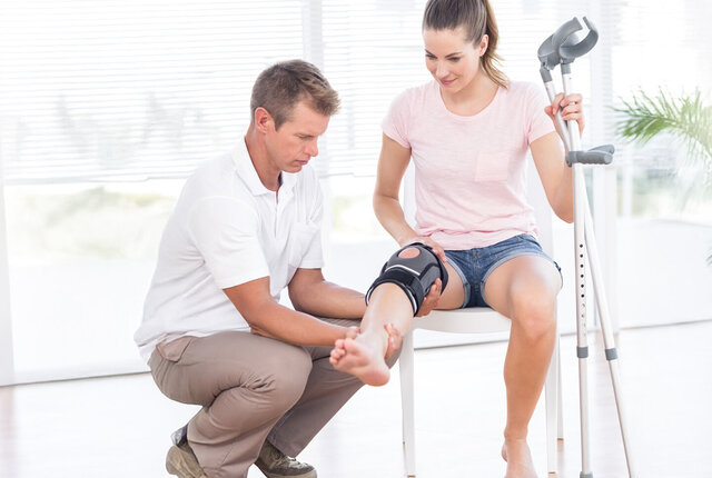 Mitarbeiter Sanitätshaus prüft Kniebandage bei einer Kundin