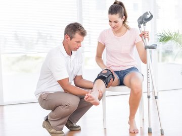 Mitarbeiter Sanitätshaus prüft Kniebandage bei einer Kundin