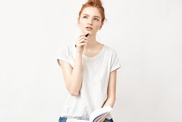 Weibliche Person überlegt, während Sie ein Notizbuch in der Hand hält – Symbolbild für Abrechnung der Hygienepauschale – gut zu wissen