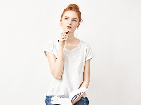 Weibliche Person überlegt, während Sie ein Notizbuch in der Hand hält – Symbolbild für Abrechnung der Hygienepauschale – gut zu wissen