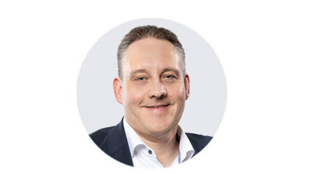 Porträtaufnahme von Sales Manager Peter Fonrobert mit kurzer, heller Frisur, hellem Hemd und dunklem Sakko vor neutralem Hintergrund.