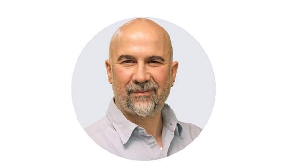 Porträt von Andreas Österholz, Physiotherapie Österholz, mit Glatze, grauem Bart und hellem Hemd.