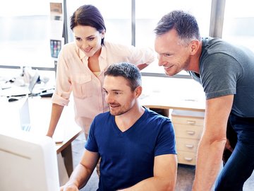 Drei Personen schauen gemeinsam auf einen Bildschirm – digitale Telematikinfrastruktur-Lösungen für Leistungserbringer im Gesundheitswesen.