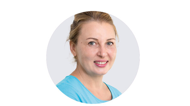 Porträt von Tatjana Kandlen, Physio Fit Mannheim, lächelnd mit blonden, zurückgebundenen Haaren und hellblauem Oberteil.