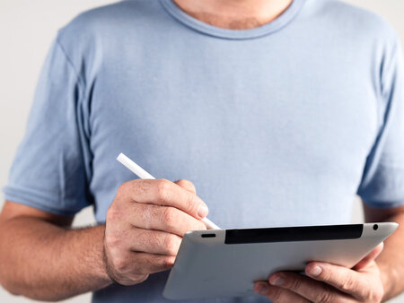Person hält Tablet in der Hand und tippt mit dem Eingabestifft