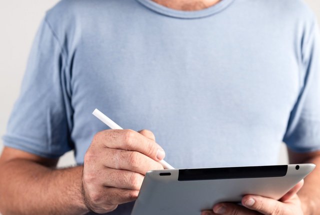 Person hält Tablet in der Hand und tippt mit dem Eingabestifft