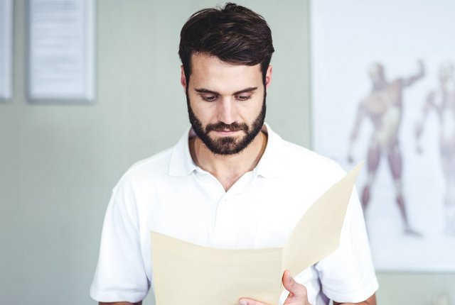 Physiotherapeut liest ein Dokument – Symbolbild für Heilmittel – was Heilmittelerbringer wissen sollten