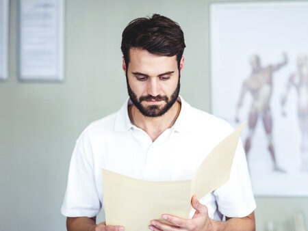 Physiotherapeut liest ein Dokument – Symbolbild für Heilmittel – was Heilmittelerbringer wissen sollten