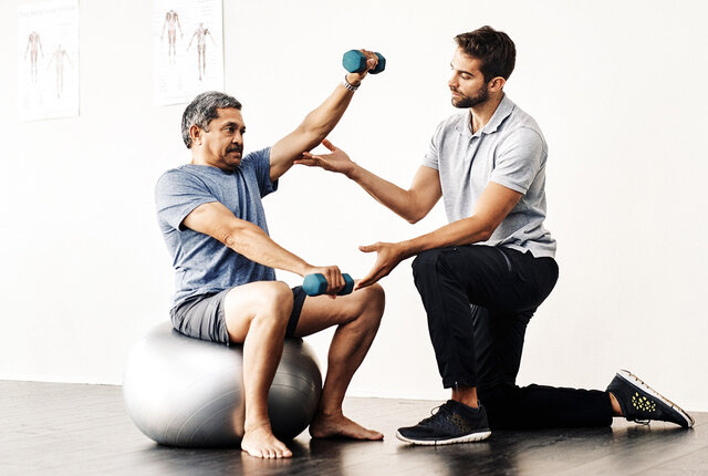 Physiotherapeut unterstützt älteren Patienten beim Training mit Hanteln – Symbolbild für moderne Physiotherapiepraxis und Vorbereitung auf die Telematikinfrastruktur-Förderung.