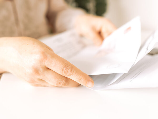 Frauenhände halten einen Briefumschlag – Symbolbild für Zuzahlung im Heilmittelbereich