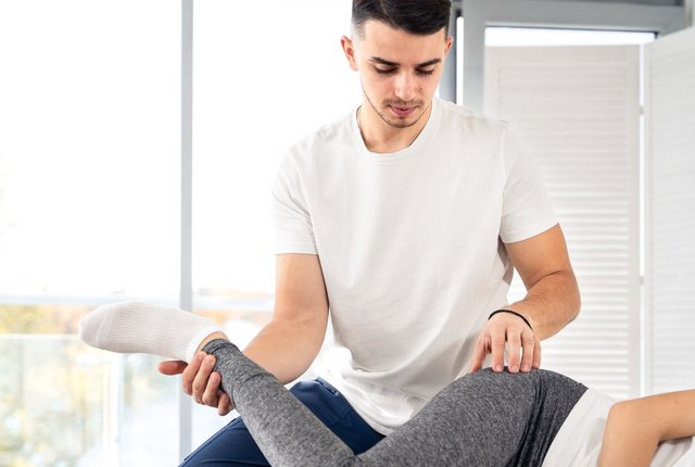 Physiotherapeut behandelt Patientin am Hüftgelenk