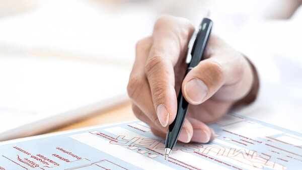 Hand mit Kugelschreiber füllt Heilmitterlverordnung Muster 13 aus