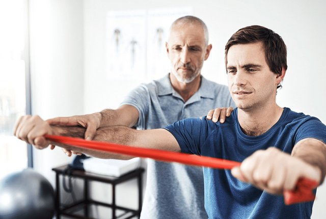 Therapeut unterstützt Patienten beim Krafttraining – Ergotherapie korrekt abrechnen mit NOVENTI.