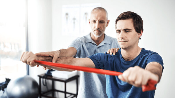Therapeut unterstützt Patienten beim Krafttraining – Ergotherapie korrekt abrechnen mit NOVENTI.