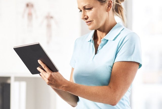 Physiotherapeut liest auf dem Tablet – Symbolbild für Wichtige Tipps zur neuen Heilmittelrichtlinie