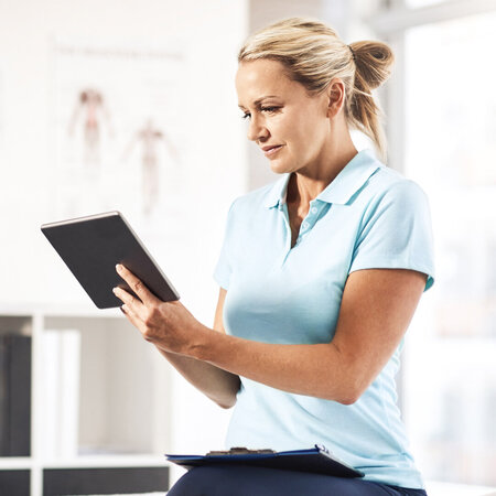 Physiotherapeut liest auf dem Tablet – Symbolbild für Wichtige Tipps zur neuen Heilmittelrichtlinie