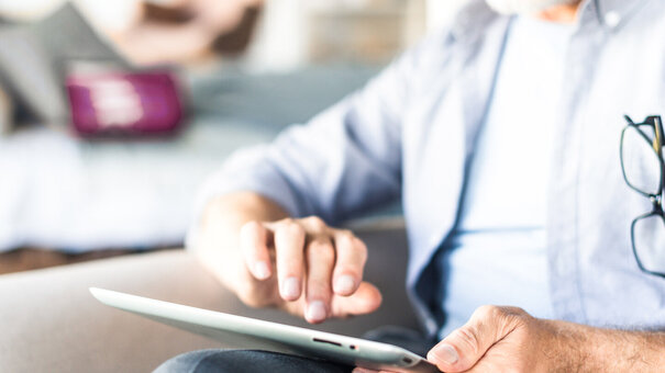 Mann benutzt ein Tablet – Symbolbild für Heilmittelkatalog – richtig nutzen, sorgenfrei abrechnen