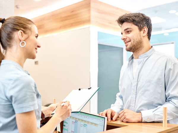 Empfangsmitarbeiterin, die einen neuen Patienten begrüßt