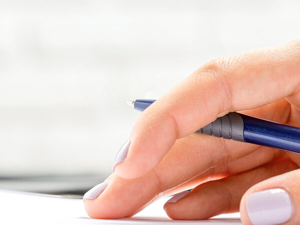 Hand mit Stift auf einem Schreibblock - Symbolbild für Heilmittelverordnung Korrekturmöglichkeiten