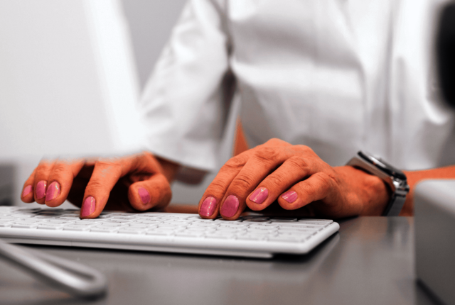 Weibliche Person tippt auf einer Tastatur – Symbolbild für ICD 10 Code und Diagnosegruppe – eine Übersicht