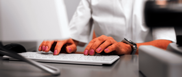 Weibliche Person tippt auf einer Tastatur – Symbolbild für ICD 10 Code und Diagnosegruppe – eine Übersicht