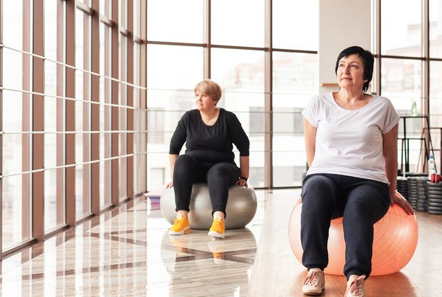 Zwei Frauen bei Rehasport-Übungen auf Gymnastikbällen in einem Trainingsraum – ambulante Bewegungstherapie mit digitaler Abrechnungslösung von NOVENTI.