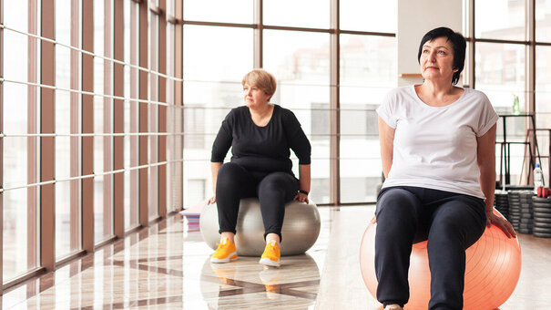 Zwei Frauen bei Rehasport-Übungen auf Gymnastikbällen in einem Trainingsraum – ambulante Bewegungstherapie mit digitaler Abrechnungslösung von NOVENTI.