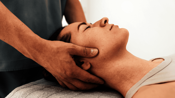 Therapeut behandelt Nacken einer Patientin – Abrechnung für Massageleistungen mit NOVENTI.