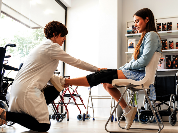Orthopädin legt einer jungen Patientin eine Knieorthese an – Symbolbild für Hilfsmittelverordnung – das sollten Hilfsmittelanbieter wissen