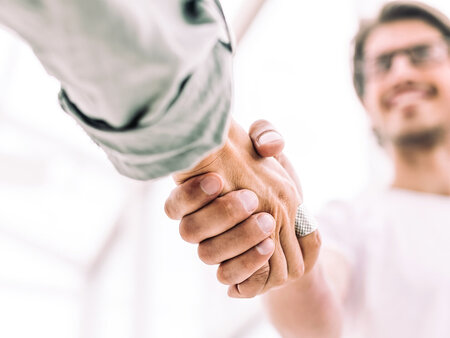 Zwei Personen geben sich die Hand, Nahaufnahme des Händedrucks als Symbol für Zusammenarbeit und Partnerschaft.