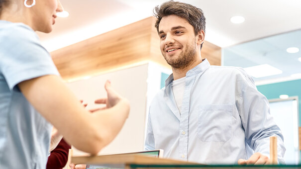 Therapeutin spricht mit einem Patienten an der Rezeption – Symbolbild für Weniger Stress am Empfang