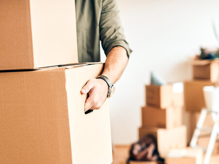 Männliche Person trägt Umzugskartons – Symbolbild für Praxisübergabe oder Praxisverlegung: So bereiten Sie Ihre Verordnungen richtig vor