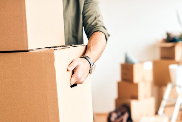 Männliche Person trägt Umzugskartons – Symbolbild für Praxisübergabe oder Praxisverlegung: So bereiten Sie Ihre Verordnungen richtig vor