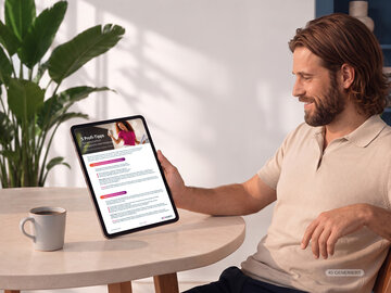 Lächelnder Mann hält ein Tablet mit dem NOVENTI-Ratgeber „5 Profi-Tipps für wirtschaftlich erfolgreiche Heilmittelpraxen“.